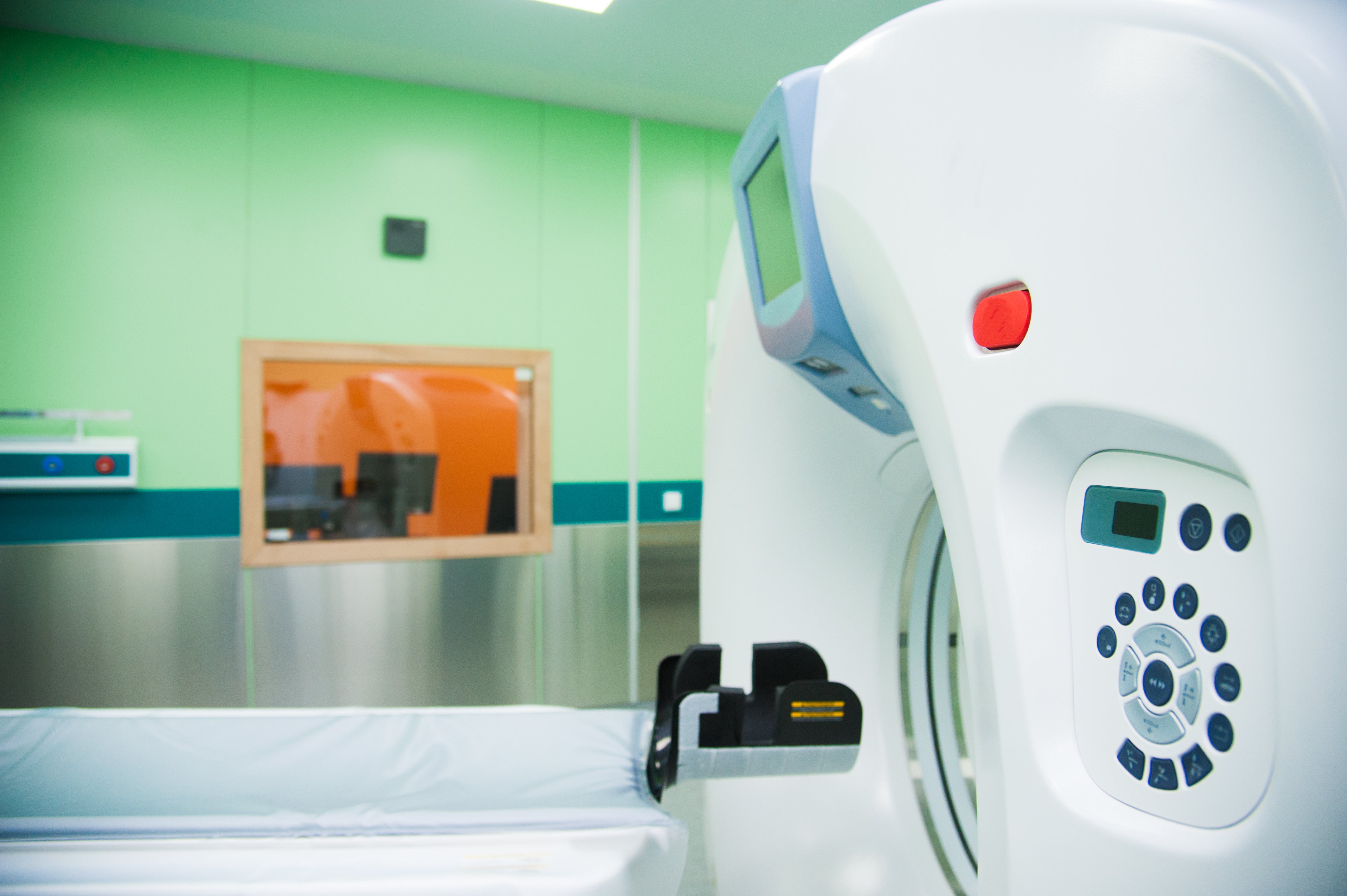 CT scanner gantry and control panel in hospital diagnostic imaging room